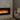 A wall-mounted electric fireplace glows inside a marble wall beside a gray sofa with neutral pillows.
