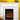 An electric fireplace's white mantel features pumpkins and lanterns. It sits beside a yellow armchair near a yellow wall.